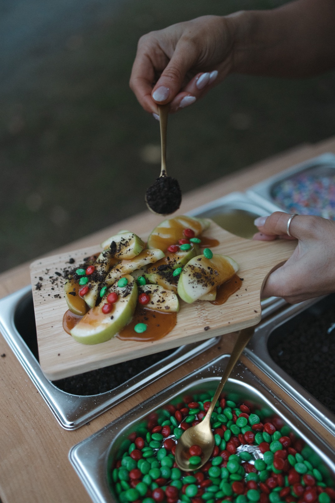 Apple slices topped with caramel, cookie crumble, and red and green candy pieces