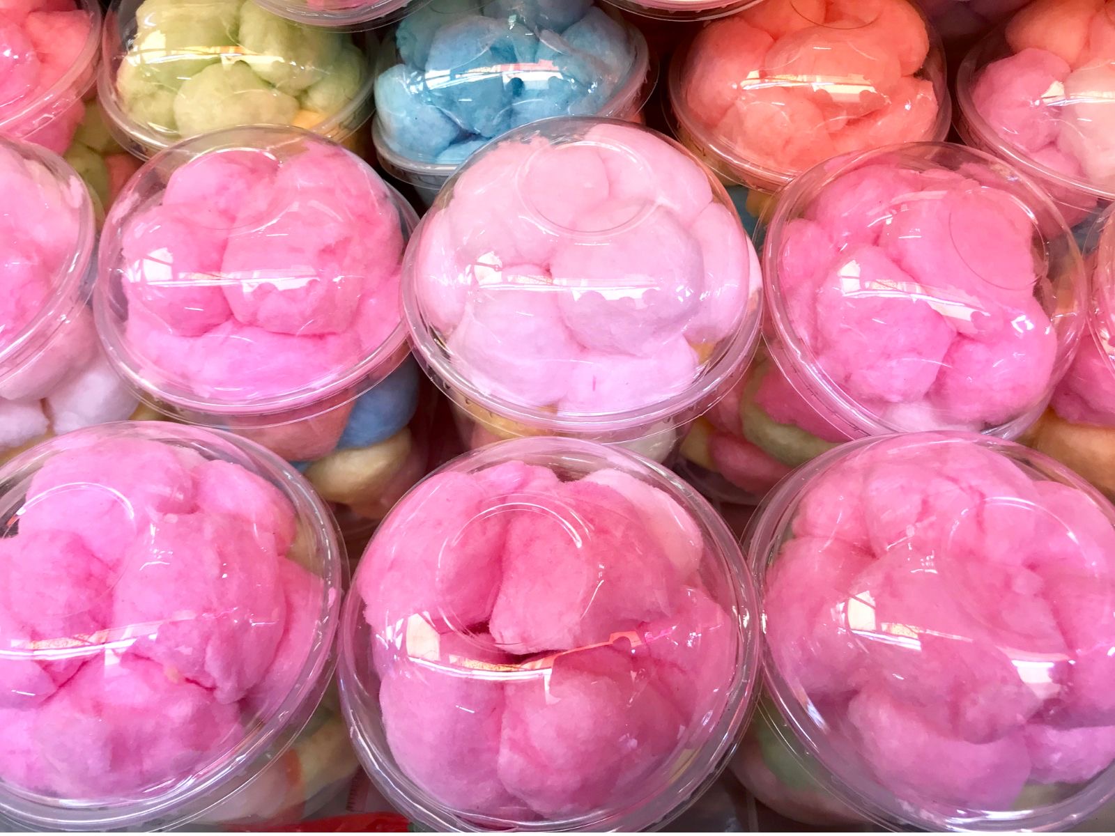 Individual cups of cotton candy in white, pink, and orange, packaged for easy serving