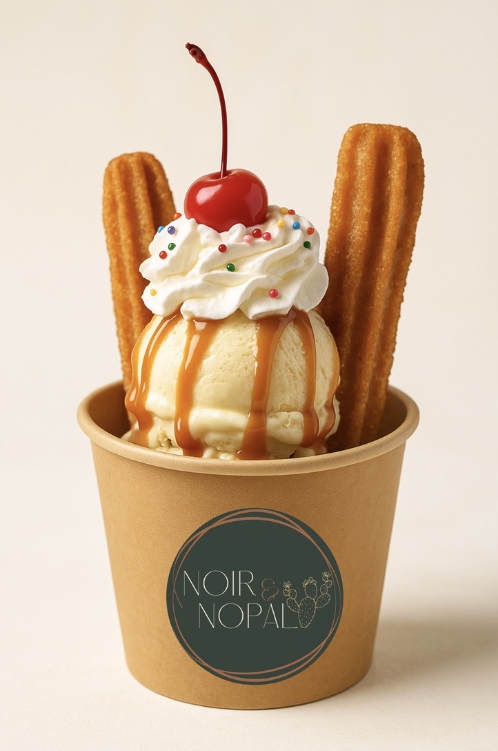 A finished churro sundae in a branded cup, with two churros, whipped cream, caramel drizzle, and a cherry