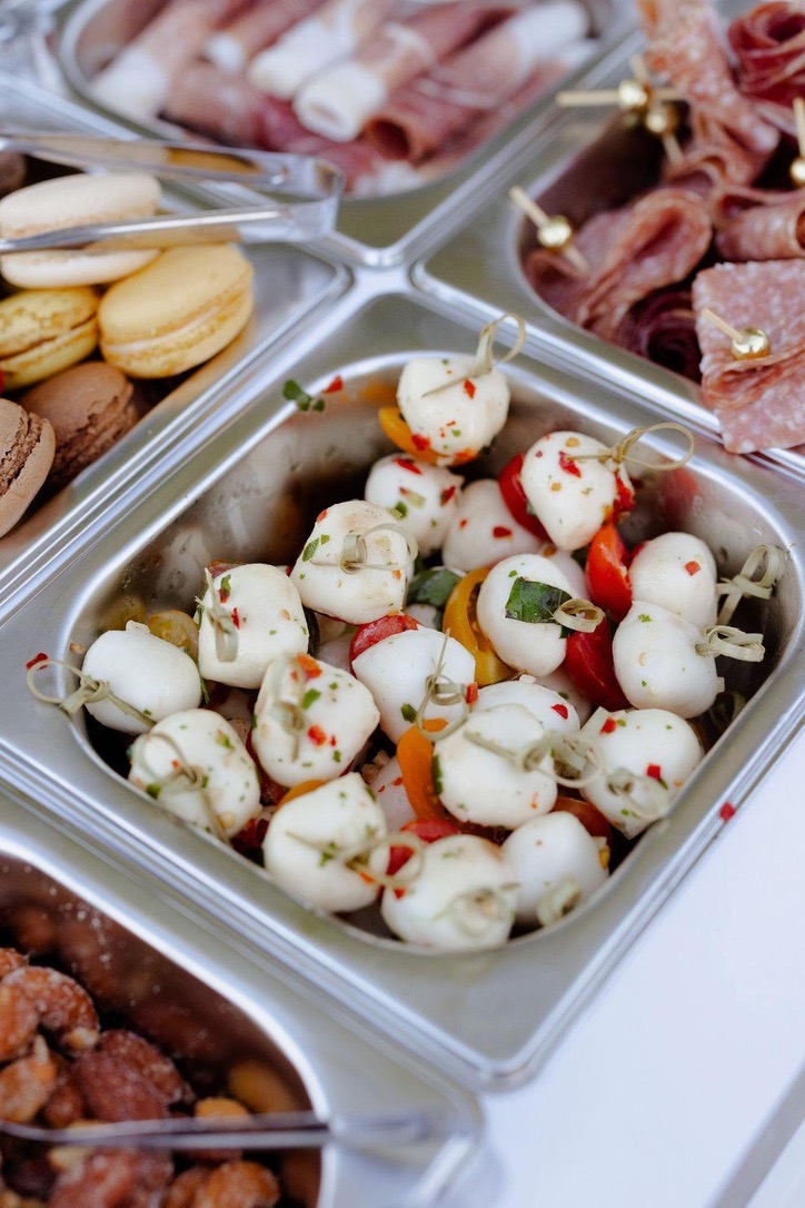 A closer view of marinated mozzarella skewers, with macarons and cured meats nearby