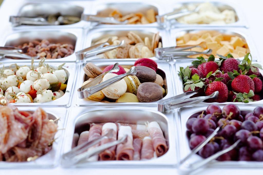 A sweet and savory spread with macarons, cured meats, mozzarella skewers, and fresh strawberries and grapes