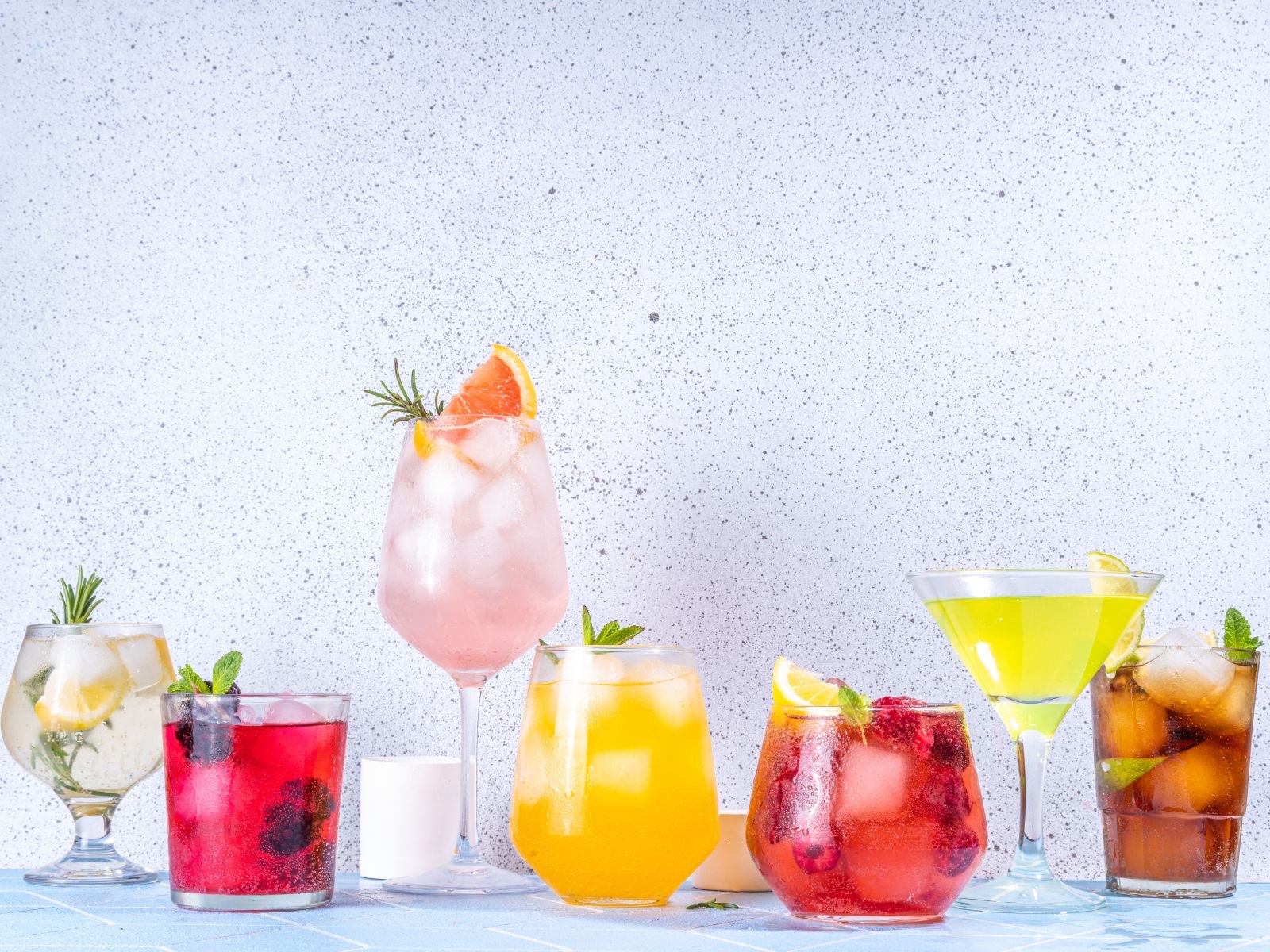 A colorful lineup of mocktails in assorted glassware, garnished with citrus and herbs