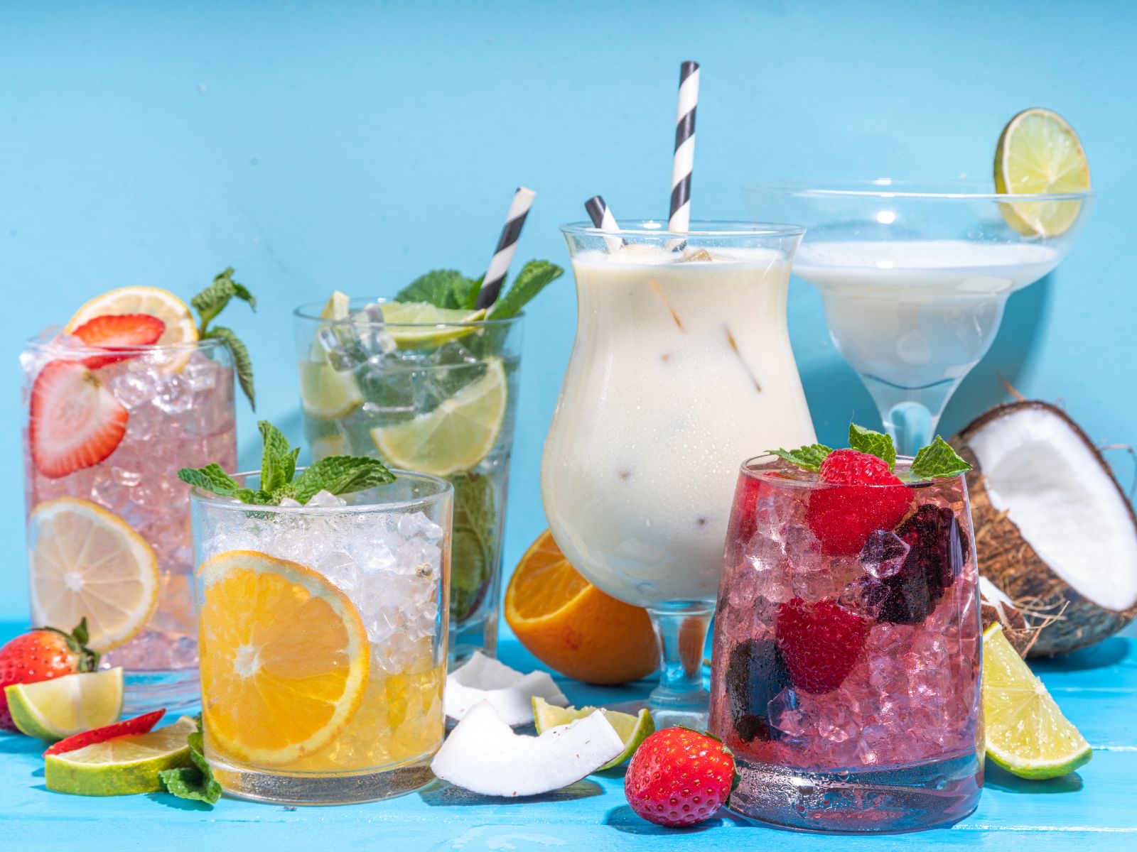 A tropical lineup of mocktails garnished with citrus, berries, and coconut