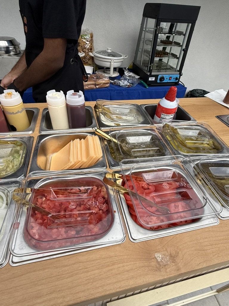 A wider view of the savory topping bar, with a warming cabinet and staff serving behind