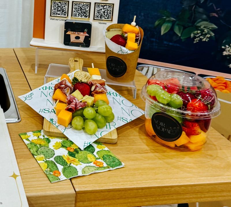 Branded Nopal Cup fruit cups with tajín, chamoy, and a fruit and charcuterie skewer, displayed on the cart