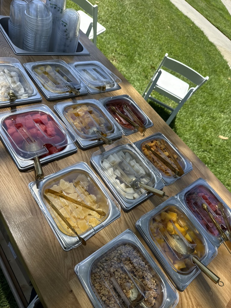 An overhead view of the full topping bar, trays of fruit and toppings ready to build cups to order