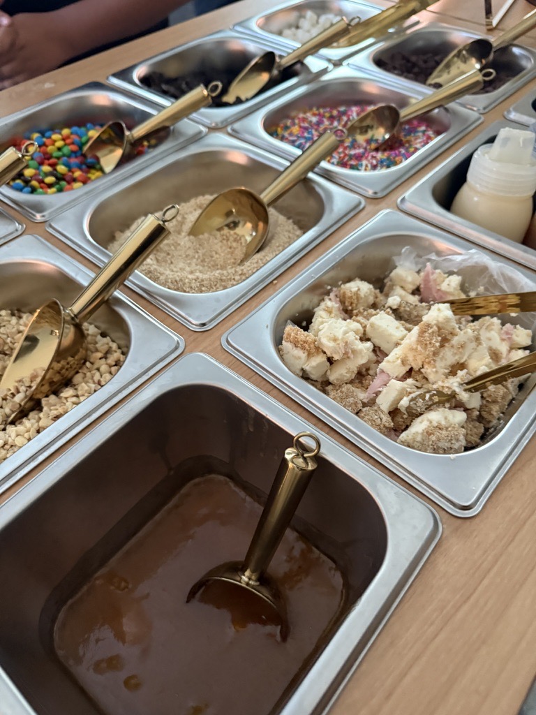 A closer view of the topping bar, with caramel sauce, crushed cookies, and sprinkles